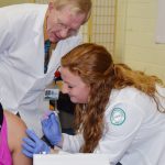 George Gartley, Nursing Instructor at NMCC, assists a student with giving a flu shot to a patient.
